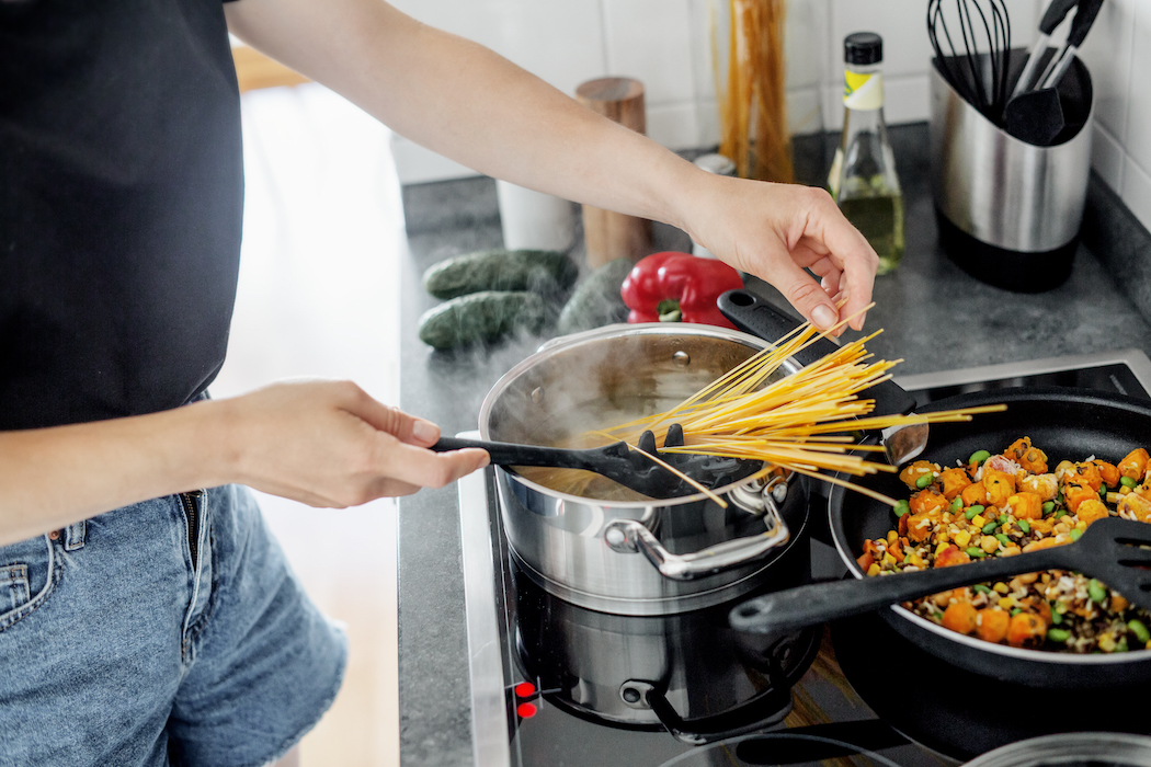 woman cooking pasta and vegetables